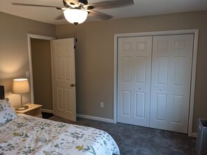 A bedroom with a bed, a nightstand, a lamp, a ceiling fan, and a set of double doors. - Carter #5, Private Two Bed near Xavier, Downtown (Cincinnati)