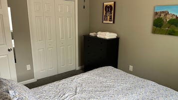 A bedroom with a bed, a dresser, a closet, and two wall art pieces.