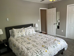 A bedroom with a bed, nightstand, lamp, and a door leading to another room. - Carter #3, Two bedroom unit near Xavier, Downtown (Cincinnati)