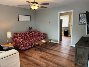 A living room with a red floral sofa, a wooden coffee table, a ceiling fan, and a framed picture on the wall. - Carter #3, Two bedroom unit near Xavier, Downtown (Cincinnati)
