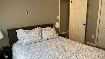 A bedroom with a bed, a nightstand, a lamp, and a door.