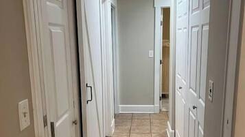 Un pasillo con puertas blancas y suelo de baldosas color beige.