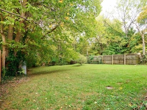 A backyard with a wooden fence, trees, and a grassy lawn.