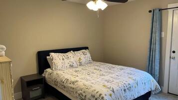 A bedroom with a bed, nightstand, and a ceiling fan.