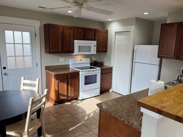 A kitchen with wooden cabinets, a white stove, a microwave, and a refrigerator.