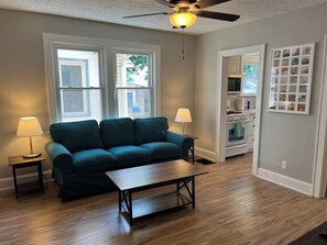 A living room with a green sofa, two lamps, a coffee table, and a ceiling fan. - Warren, 1 Bedroom Unit near Xavier, Downtown (Cincinnati)