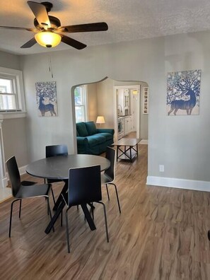 A dining area with a round table and chairs, a ceiling fan, and artwork on the walls. - Warren, 1 Bedroom Unit near Xavier, Downtown (Cincinnati)