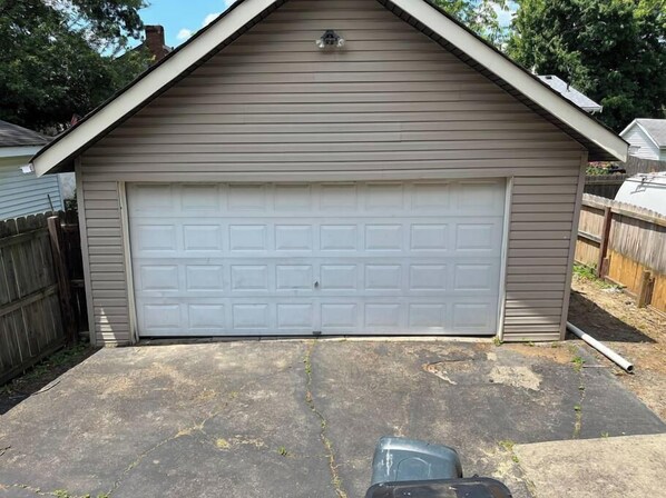 A garage with a white door, a sloped roof, and a concrete driveway.