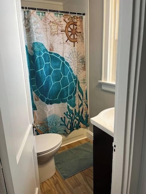 A bathroom with a nautical-themed shower curtain, a toilet, and a sink.