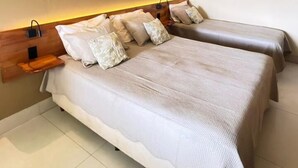 Une chambre d’hôtel avec deux lits, chacun doté d’une tête de lit en bois, de draps blancs et d’une petite table de chevet. Des appliques murales sont fixées au-dessus de chaque lit.