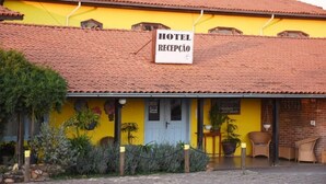 L’entrée d’un hôtel, reconnaissable à sa façade jaune, son toit en tuiles et un panneau indiquant l’emplacement de la réception.