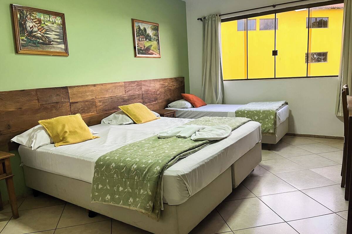 A room with two beds, a wooden headboard, and two paintings on the wall.