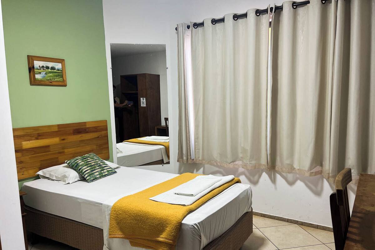 A hotel room with two beds, a wooden headboard, a yellow towel, and a painting on the wall.