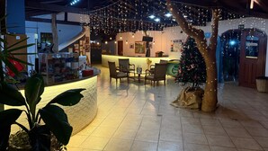 Un espace intérieur accueillant avec un comptoir d’accueil, un coin salon et un sapin de Noël.