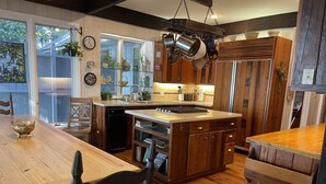 Une cuisine avec des meubles en bois, un îlot central et des ustensiles de cuisine suspendus.