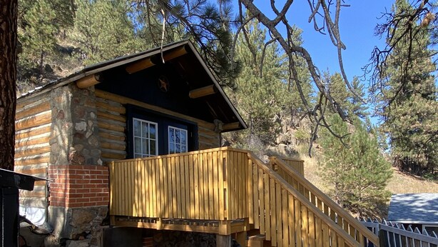 A rustic cabin with a wooden staircase leading to a porch. - Cozy Cabin (Clancy)