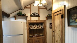 A kitchen with wooden cabinets, a white refrigerator, and a 'WELCOME' sign above the cabinets. - Cozy Cabin (Clancy)