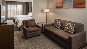 Una habitación de hotel con una cama, un sofá, una silla, un escritorio y una lámpara.