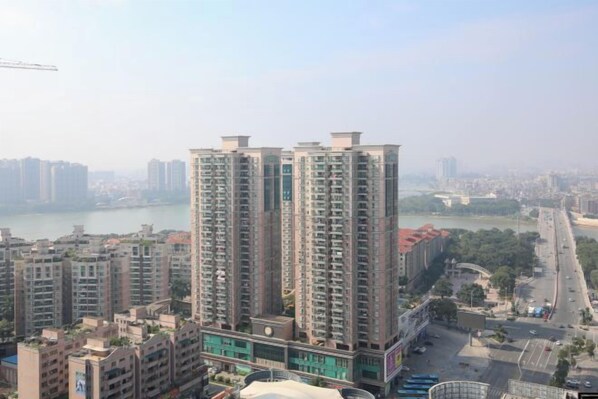 A high-rise building with multiple floors, surrounded by other buildings and a body of water in the background.
