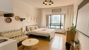 Ein modernes Schlafzimmer mit Bett, einer Couch, einem kleinen Tisch, einem Balkon mit Blick und einer Pflanze.