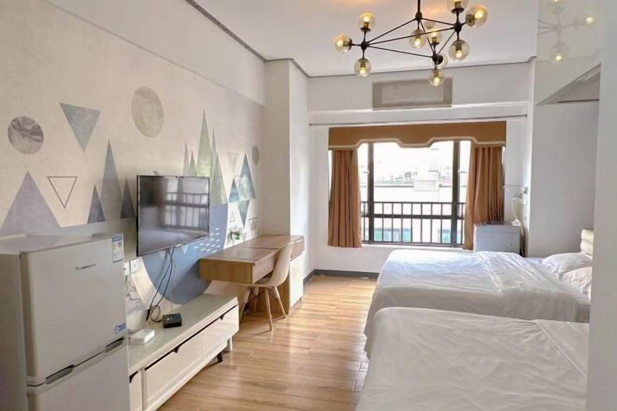 A hotel room with a bed, a desk, a television, and a window with curtains.