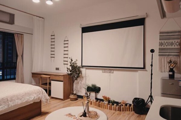 A modern bedroom with a bed, desk, and a projector screen. - Best Apartment (Dongguan Huixing Square) (Dongguan)