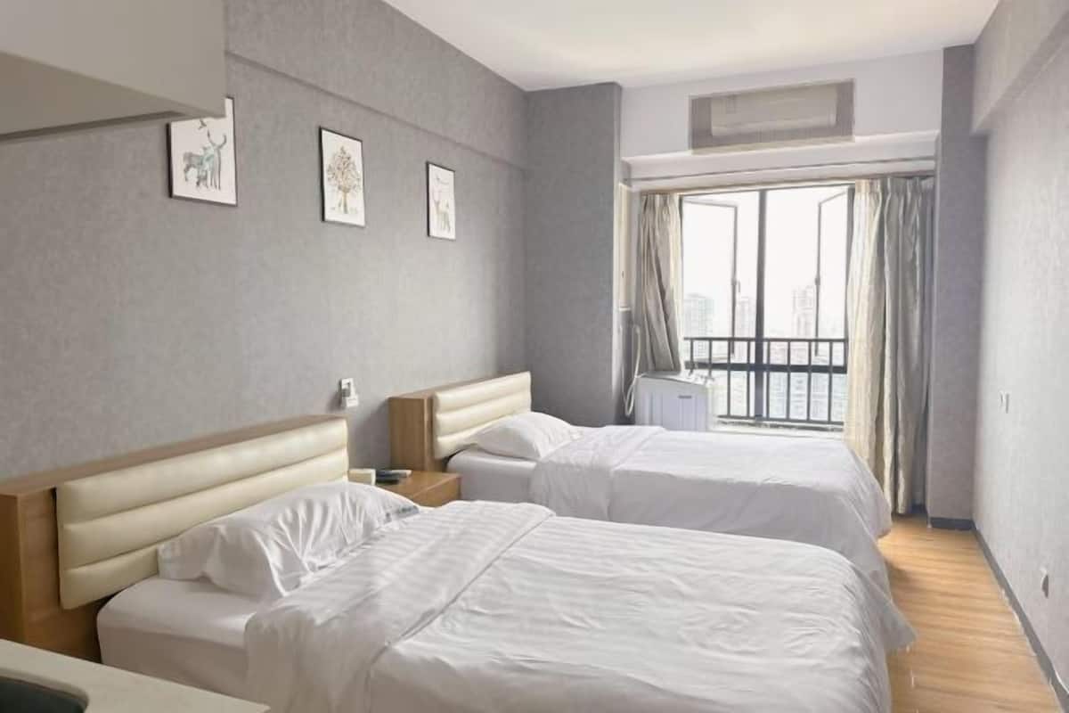 A hotel room with two beds, a window with curtains, a radiator, and wall art.