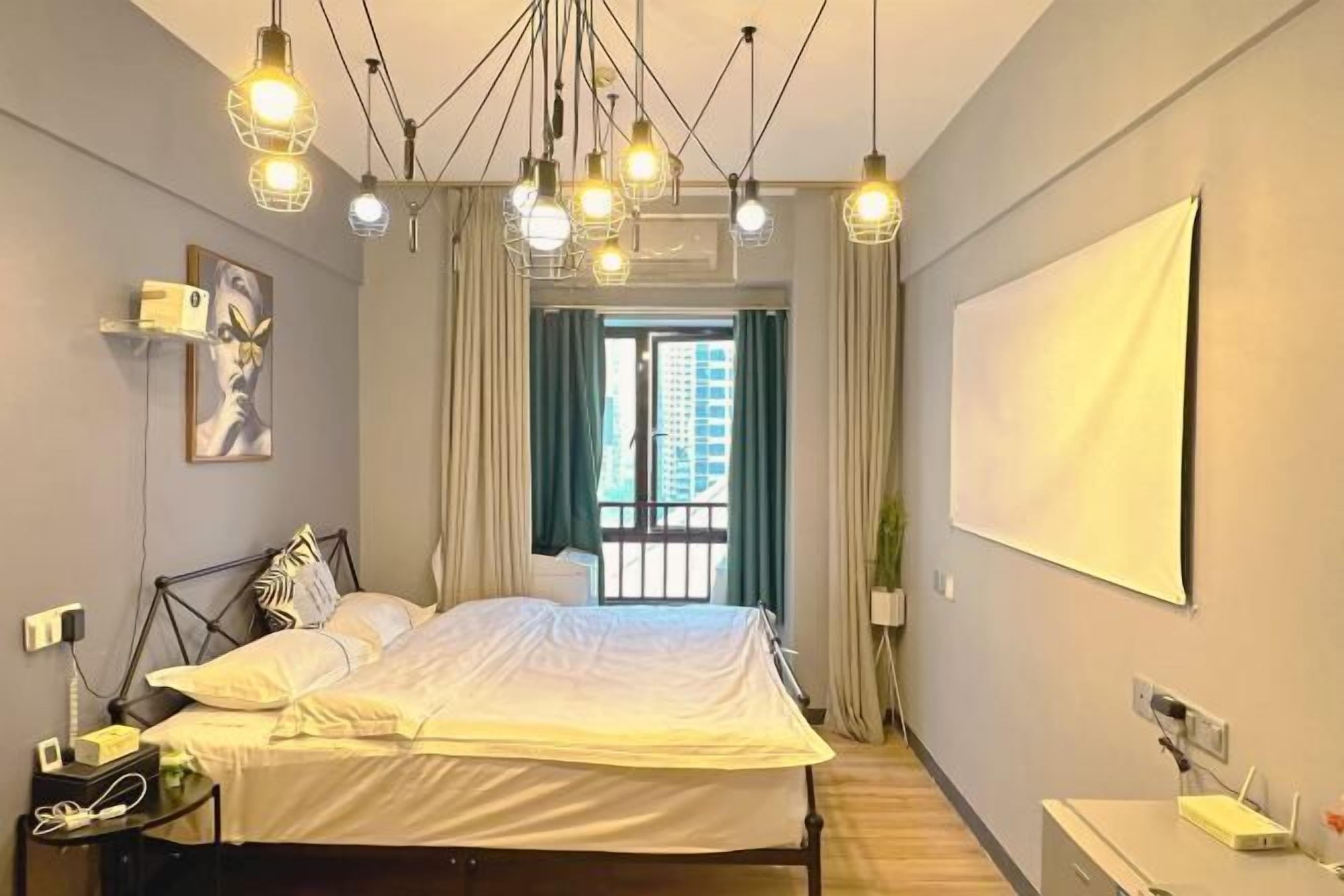 A modern bedroom with a bed, bedside table, and a large window with curtains.