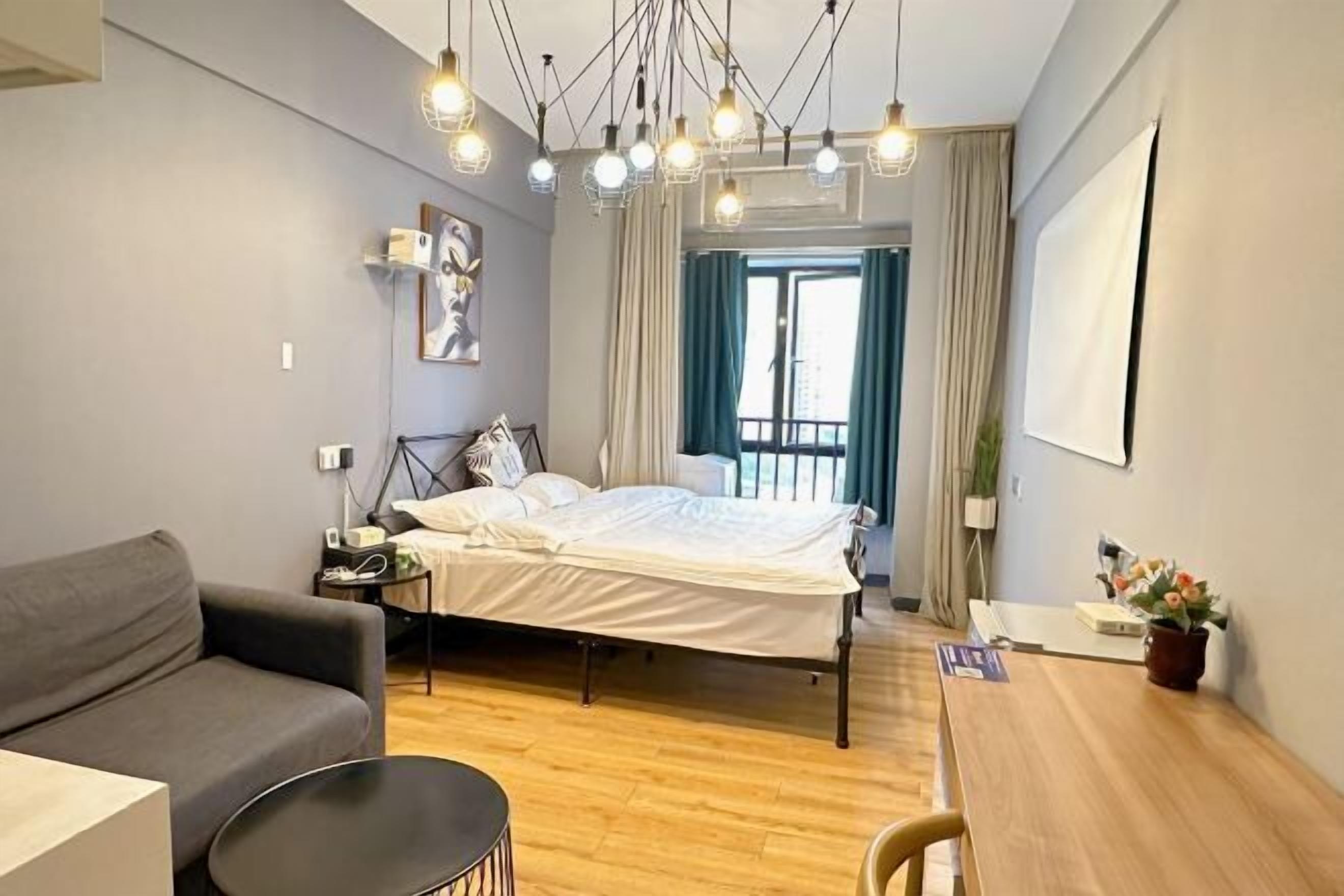 Un dormitorio moderno con cama, sofá, mesa de comedor y lámpara colgante.