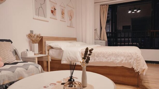 Ein Schlafzimmer mit einem Bett, einem Nachttisch und einem runden Tisch mit einer Vase.