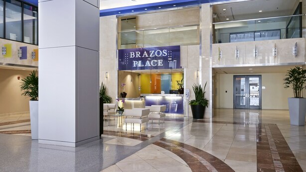 A modern lobby with a reception desk, seating area, and a large potted plant. - Luxurious 1 Bedroom Condo in Downtown Austin (Austin)