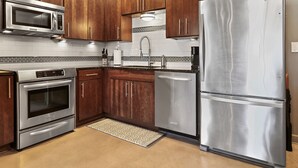 A modern kitchen with stainless steel appliances, wooden cabinets, and a tiled backsplash. - Luxurious 1 Bedroom Condo in Downtown Austin (Austin)