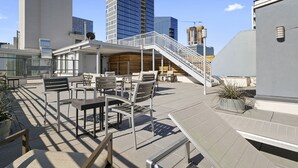 A rooftop terrace with outdoor seating, a staircase, and a view of surrounding buildings. - Luxurious 1 Bedroom Condo in Downtown Austin (Austin)