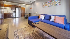 A modern living room with a blue sofa, wooden coffee table, and patterned rug. - Luxurious 1 Bedroom Condo in Downtown Austin (Austin)