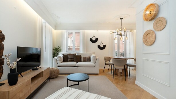 A modern living room with a sofa, TV, and dining area. - GuestReady - Modern and exquisite apt near Estrela (Lisbon)