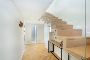 Stairs lead to an upper level with a door at the bottom, set against a backdrop of white walls and light wood floors.