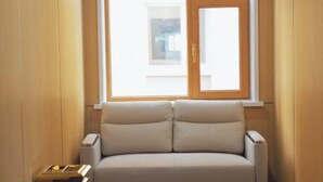 A room with a window, a sofa, and a small table. - OYO Ulanhot Huide Business Hotel (Ulanhot)
