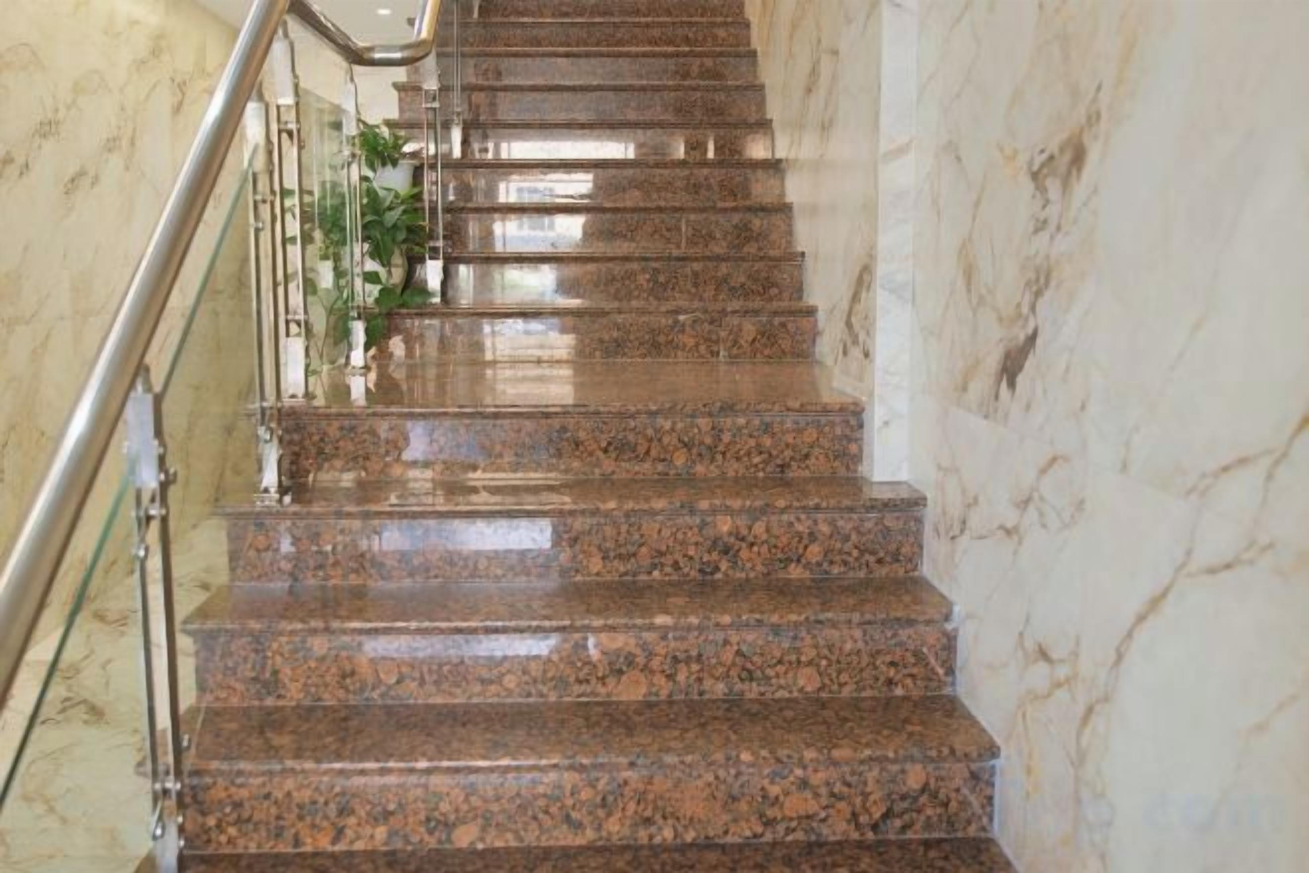 Una escalera de mármol con barandillas de metal, que asciende.
