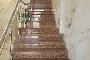 A marble staircase with metal railings, leading upwards.