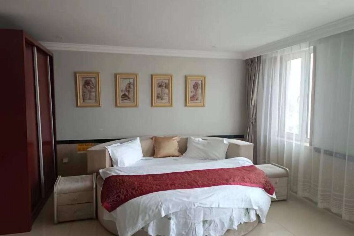 A hotel room with a bed, bedside tables, a wardrobe, and a window with curtains.