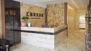 Een receptiebalie met een marmeren aanrecht en een bord met de tekst 'HUIDE BUSINESS HOTEL'.