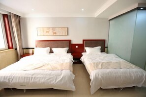 A hotel room with two beds, a large window with curtains, a painting on the wall, and a wardrobe.