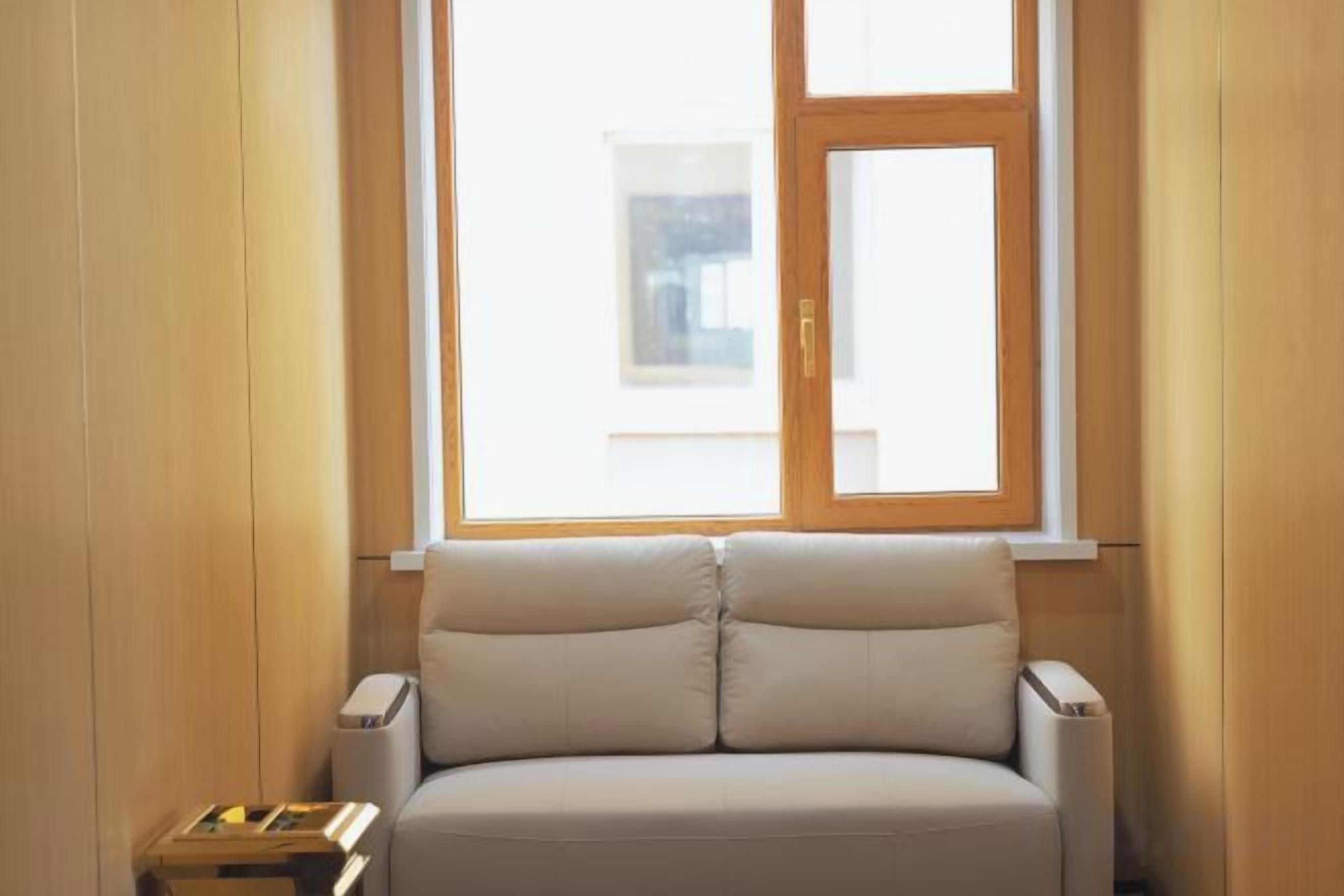 Una habitación con ventana, sofá y una pequeña mesa.