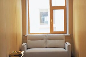 Una habitación con ventana, sofá y una pequeña mesa.