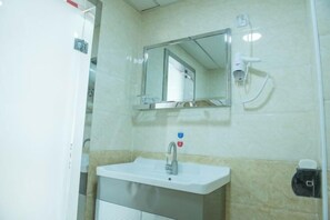 A bathroom with a sink, mirror, and a hand dryer.
