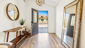 A hallway with a wooden bench, a round mirror, and a geometric light fixture. - Chic Spanish Palm Springs ~2000 square feet Pool Home (Palm Springs)