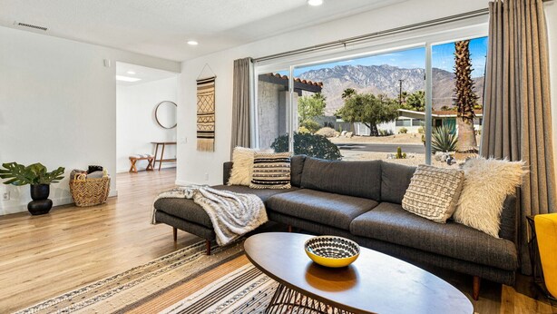A modern living room with a large window, a sofa, a coffee table, and a view of mountains. - Chic Spanish Palm Springs ~2000 square feet Pool Home (Palm Springs)