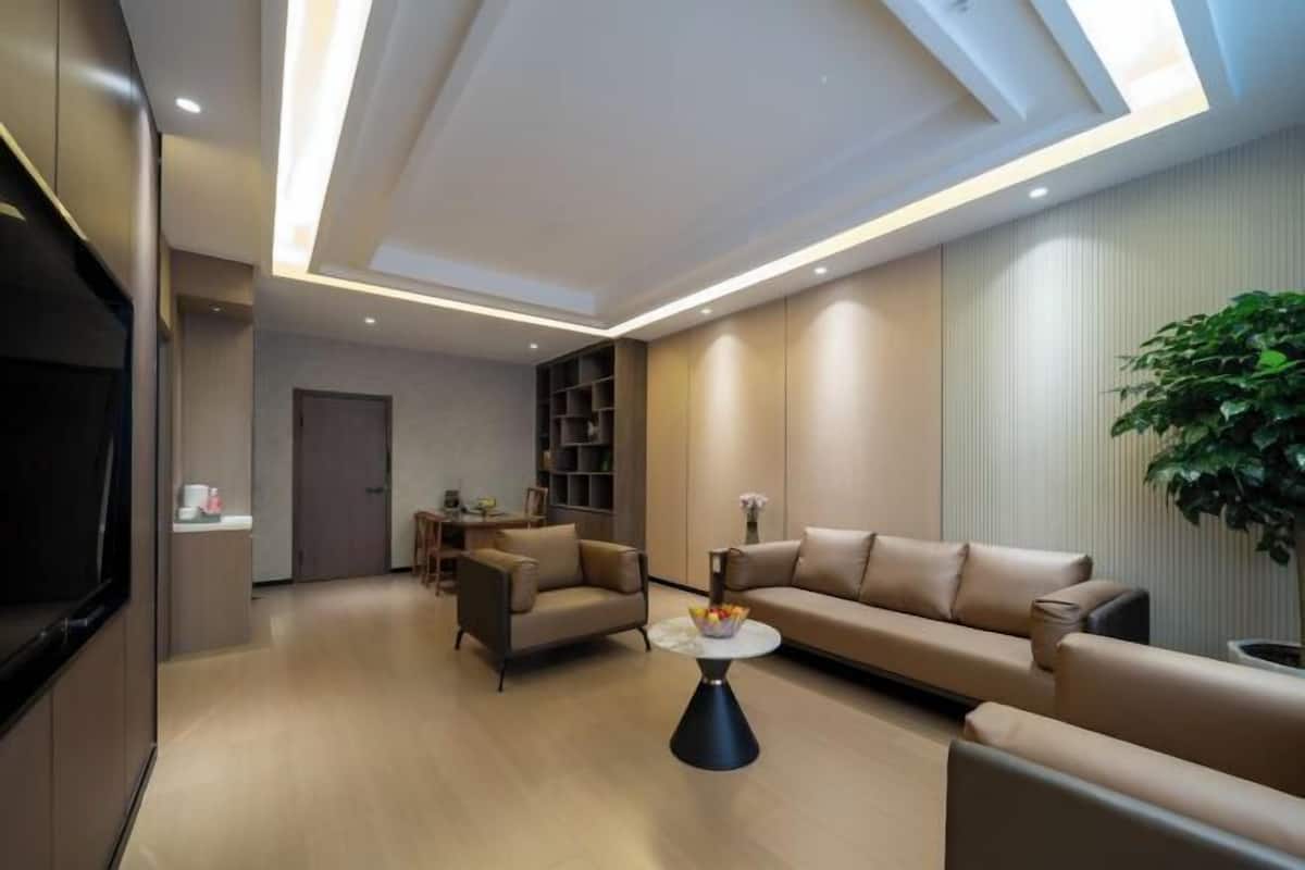 A modern living room with a sofa, armchairs, a coffee table, and a TV.