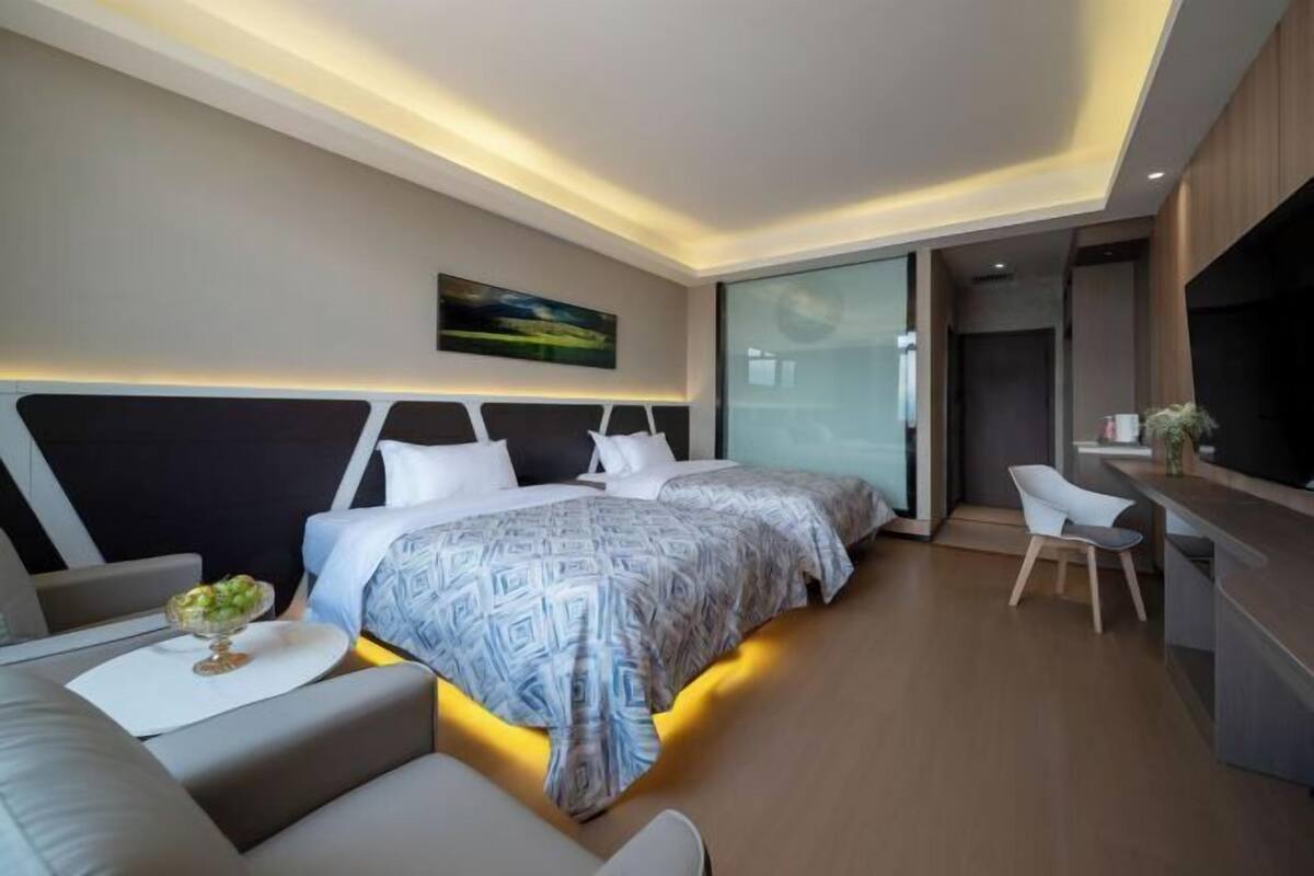 A modern hotel room with a large bed, a desk, and a seating area.
