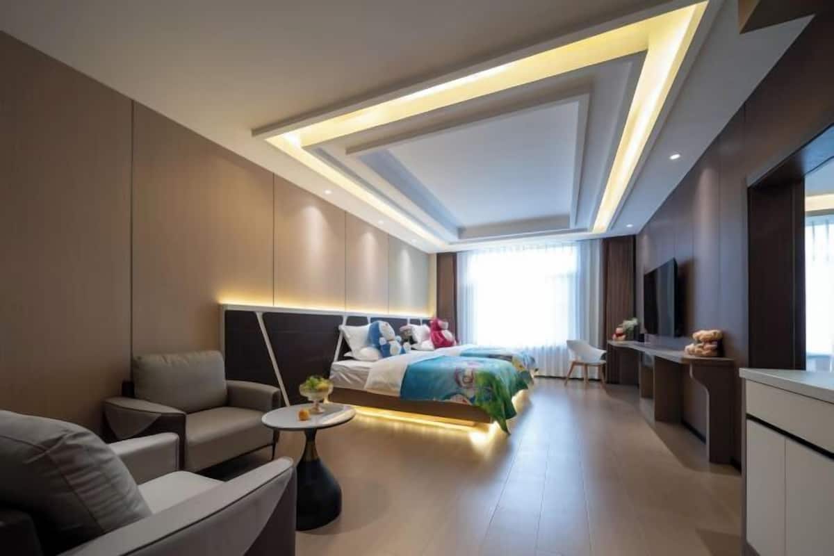 A modern hotel room with a bed, a sofa, a small table, and a TV.